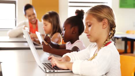 schoolgirl using laptop in classroom
