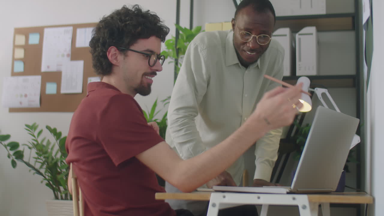 Diverse Colleagues Discussing Project on Laptop in Office