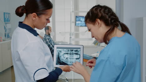 dentista y enfermera analizando la radiografía de los dientes en la tableta