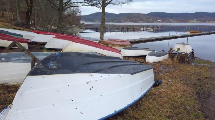 Barche a remi capovolte sulla sponda del lago per proteggerle dalla pioggia.