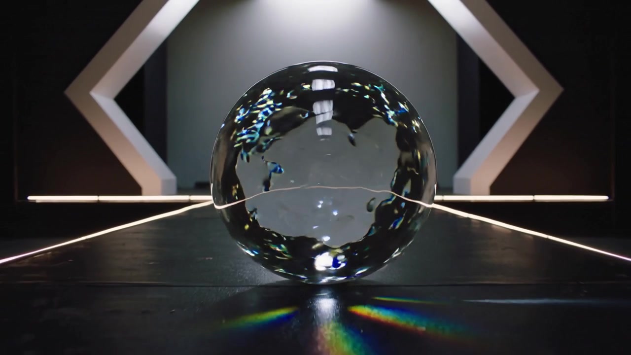 Sfera di vetro rotante che mostra il movimento delle bolle dal flusso interno su un pavimento scuro dello studio, con effetto prisma.