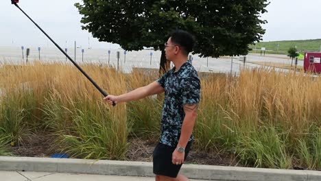 man walks with selfie stick in park