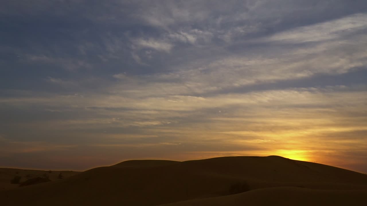 Sunset view with blue sky and white clouds over desert sands