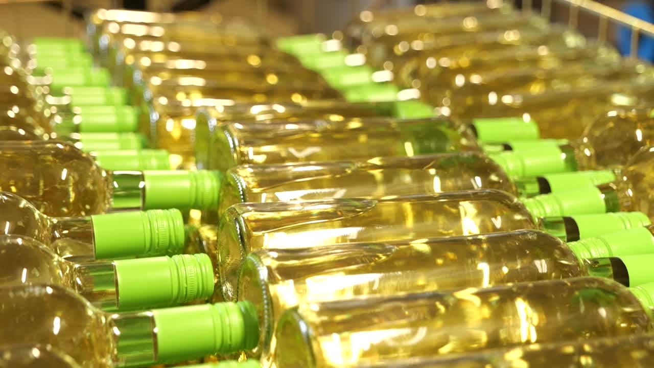 filas de botellas de vino blanco con tapas verdes listas para el embalaje