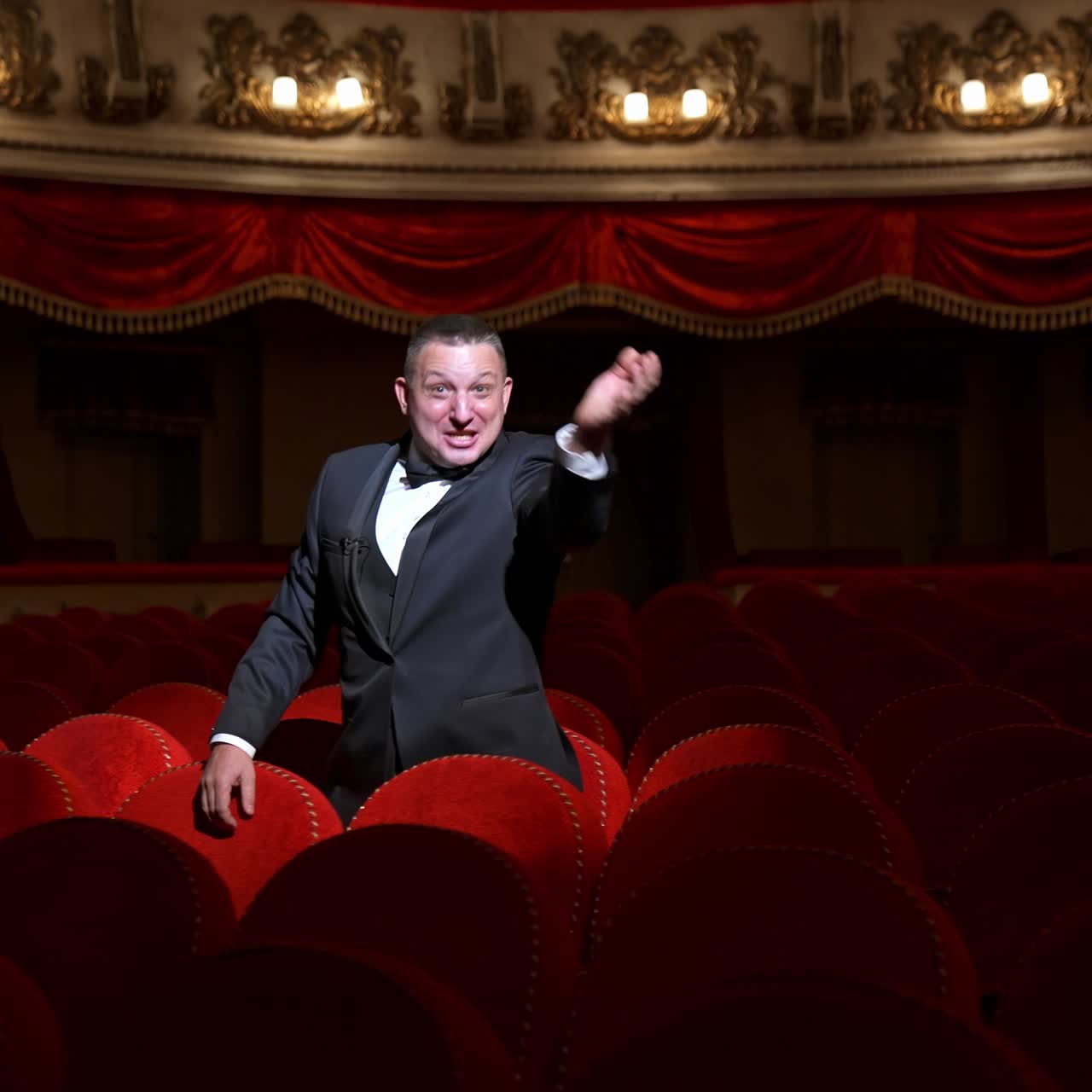 Comedian speaking in dark theater without people. Mad actor shouting in empty theatrical hall and calls someone. Consequences of pandemic