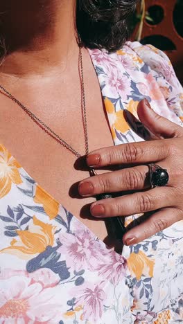 woman wearing a floral dress, necklace, and ring