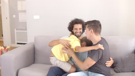 niño alegre saltando en el sofá a sus dos padres