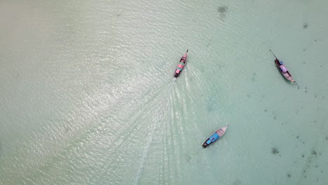 Vista-Aérea-De-Drones-De-Arriba-Hacia-Abajo-En-Un-Barco-Tailandés-Tradicional-Navegando-En-Aguas-Poco-Profundas-En-Una-Playa-De-Arena-Blanca-En-La-Isla-De-Koh-Phi-Phi-Don,-Krabi