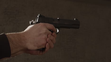 man holding and aiming pistol with his finger on the trigger