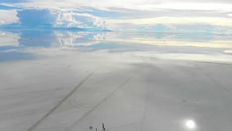aerial of people gathering on the uyuni salt flats lake with perfect reflections in bolivia