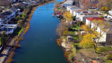 an aerial view along a neighborhood channel, running behind houses on a sunny day