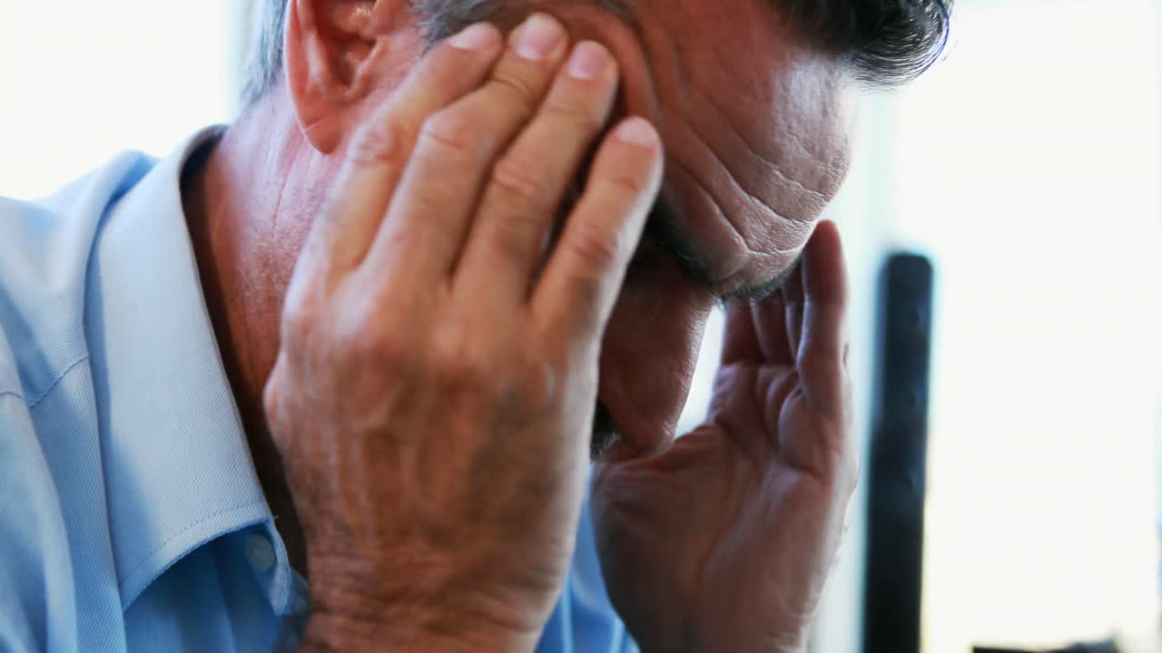 Dirigente uomo stressato seduto in ufficio 4K
