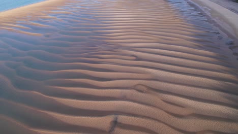 impresionante costa de arena texturizada desde arriba con piscinas acuosas y tonos azules