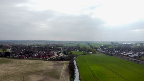 Ein-Atemberaubender-Clip-Von-Oben-über-Dem-Großartigen-Stour-Fluss-In-England,-Wie-Er-Durch-Ein-Feld-Schneidet,-Auf-Der-Einen-Seite-Lebendig,-Auf-Der-Anderen-Baren