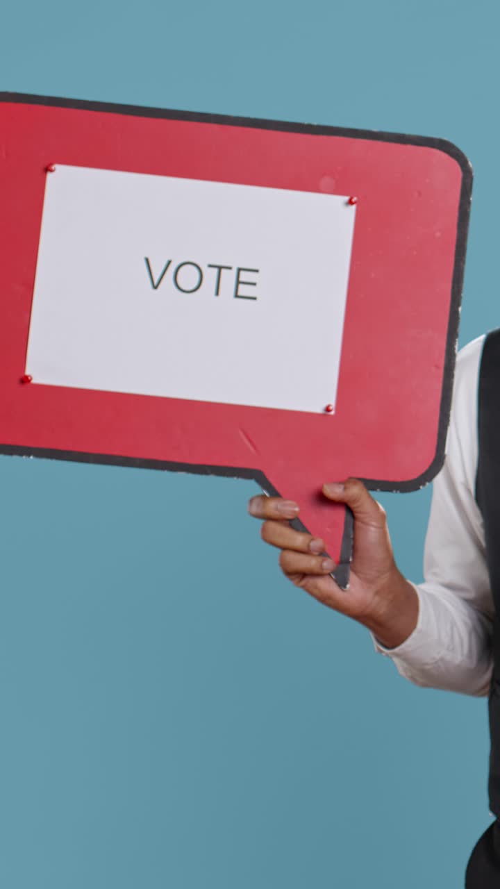 Person's Hand Holding 'Vote' Speech Bubble Sign