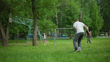 a young boy skillfully lifts a soccer ball with his leg, demonstrating his athleticism, in the background, his grandfather and younger brother can be seen