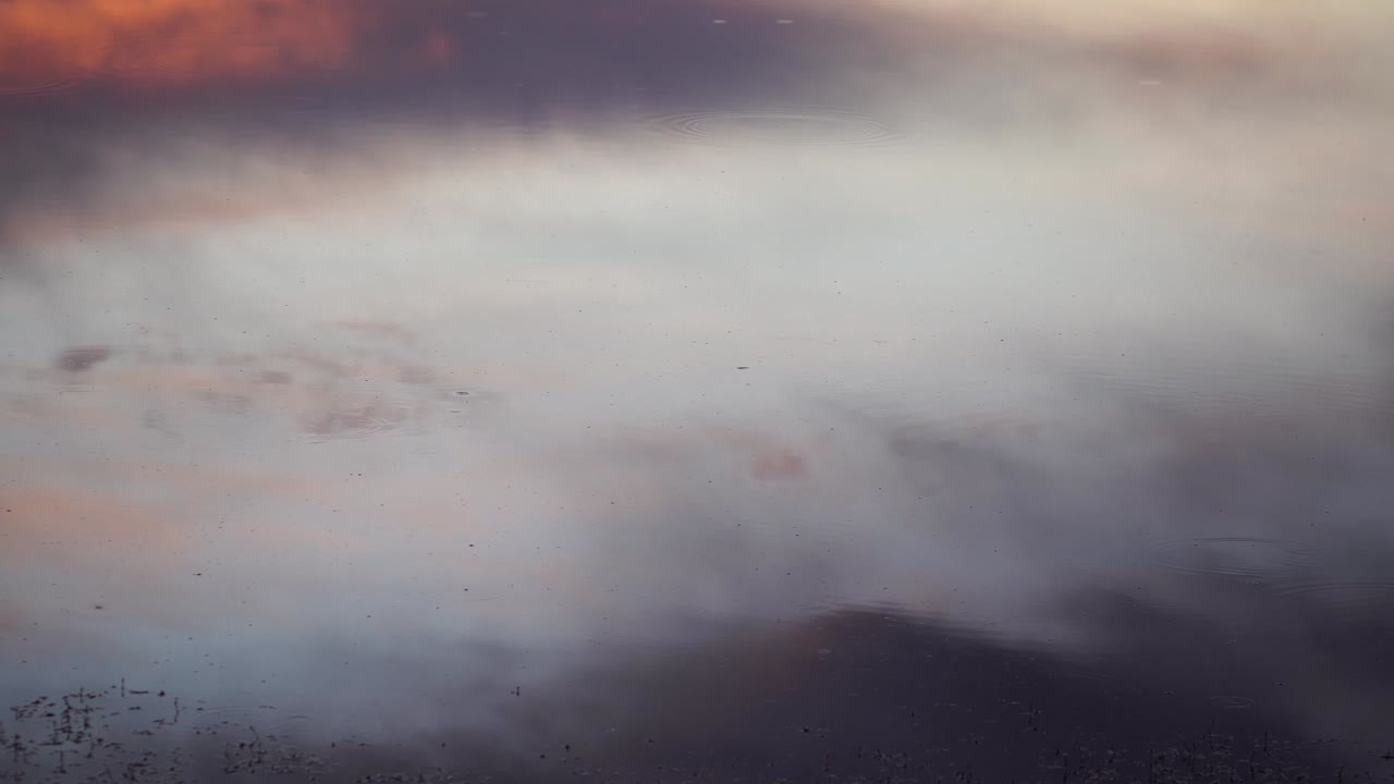 해가 지면 구름이 가득한 하늘은 여전히 저녁에 호수나 연못의 어두운 물에 반사됩니다.