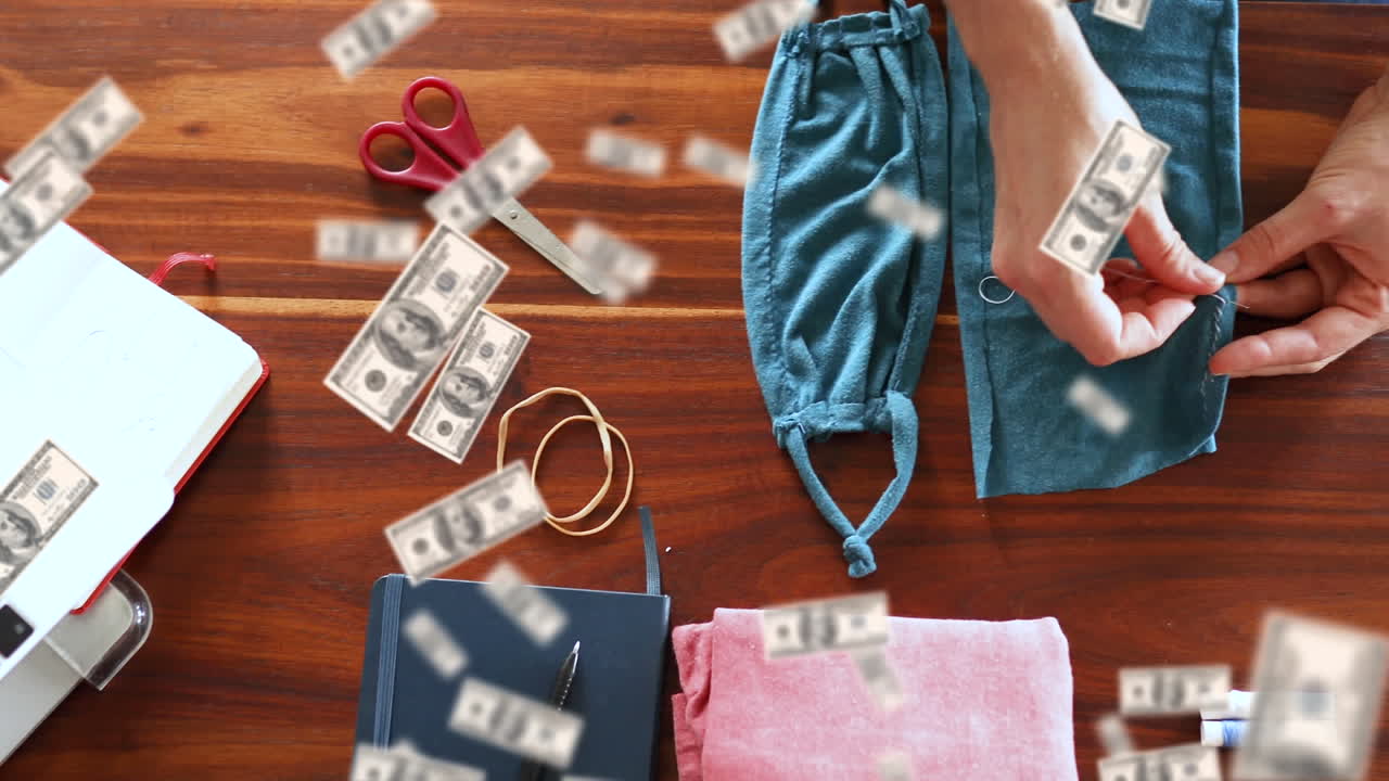 Digital composite video of american dollar bills falling over against woman sewing face masks
