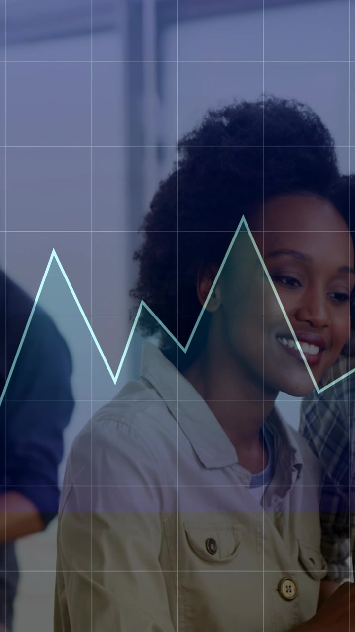 Vertical video: Man pointing tablet, woman leaning viewing office data with live graph over tablet