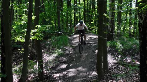 A-static-shot-in-slow-motion-of-an-adult-male-jumping-on-an-electric-bicycle-in-the-forest-with-style