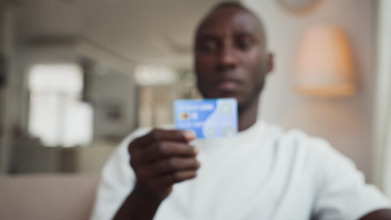 Uomo di colore che mostra una carta di credito alla telecamera in interni