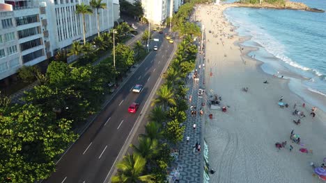 hermosa playa y avenida con coches montando por la tarde incluyendo un coche de policía en río de janeiro