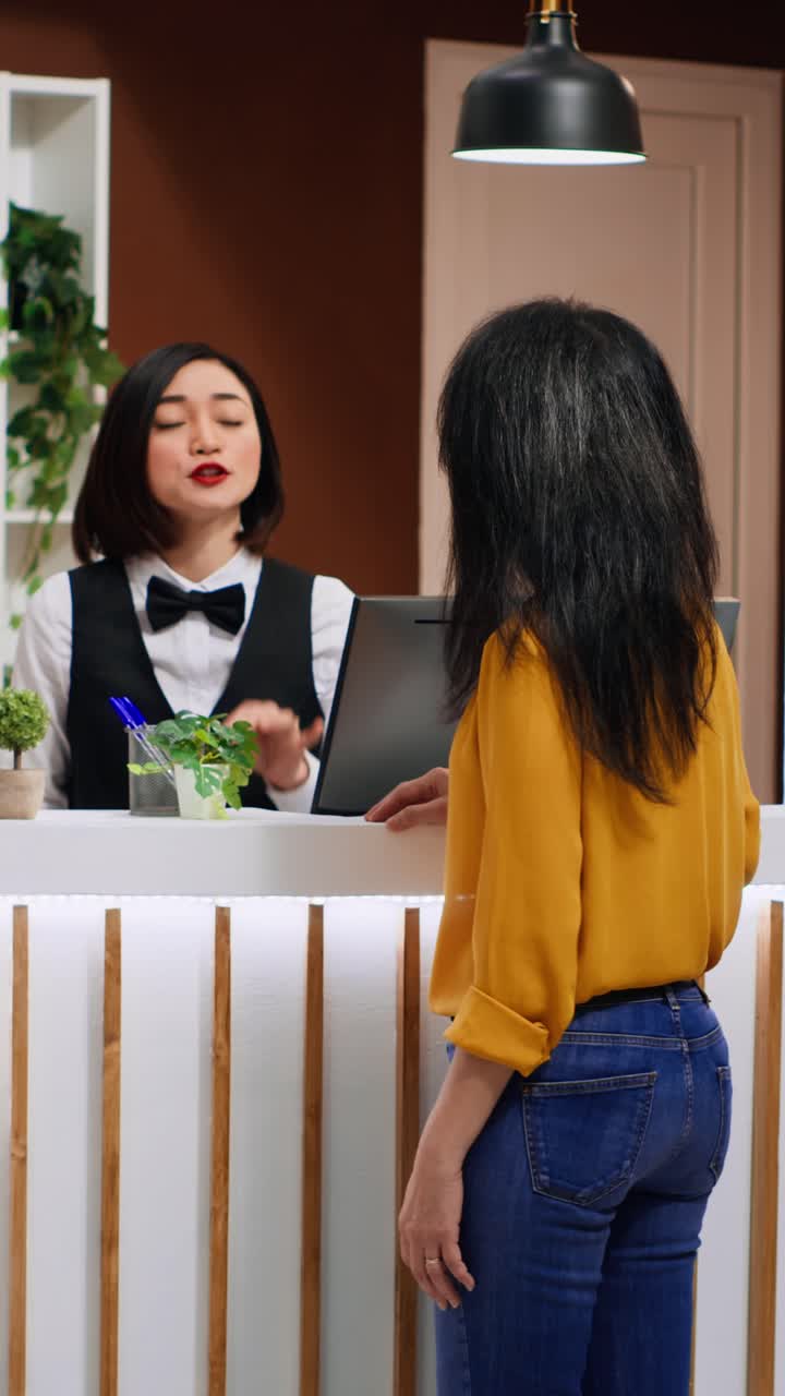 Video verticale: lavoratore asiatico che esegue la procedura di check-in per un nuovo visitatore