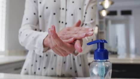 mid section of woman sanitizing her hands at home