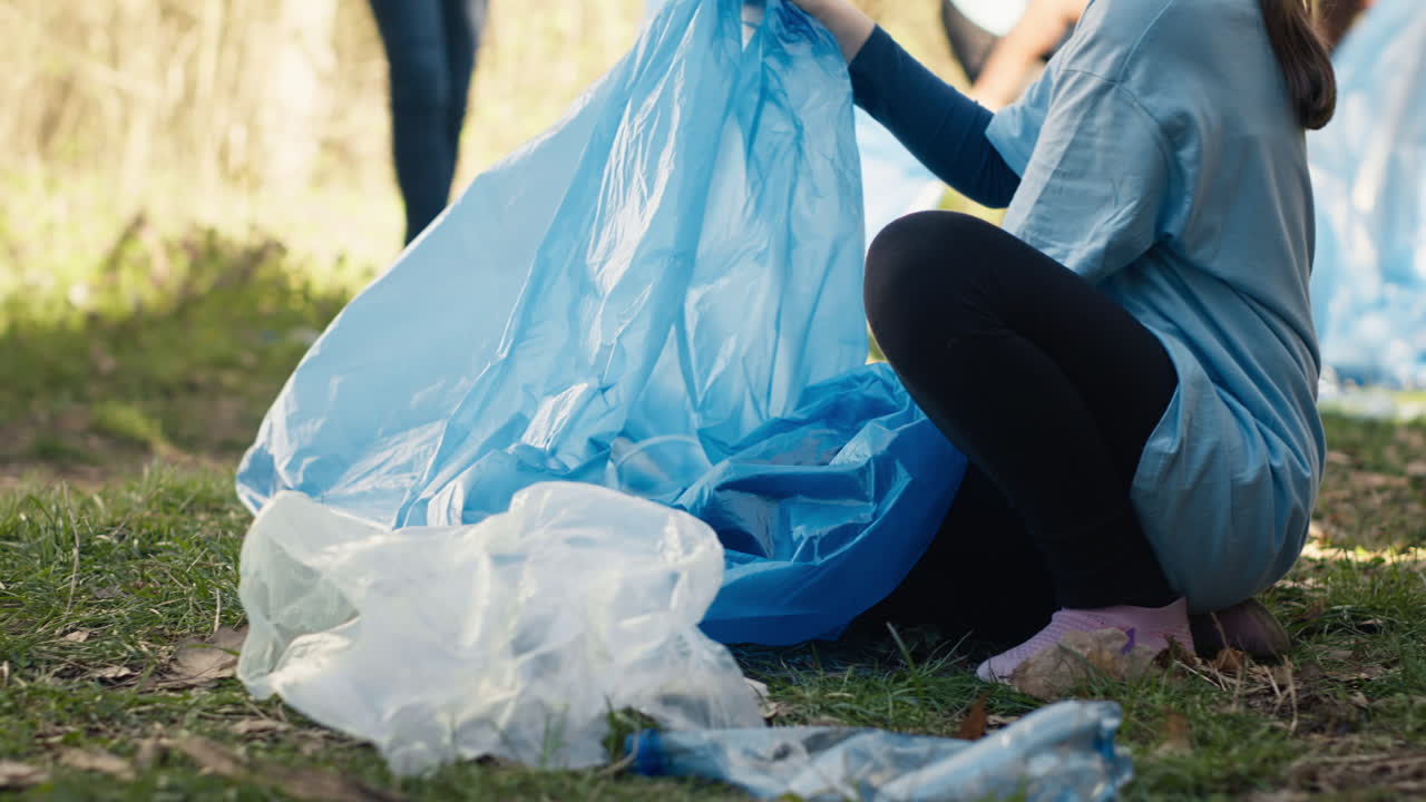 Tired little girl collecting trash and plastic bottles from the forest