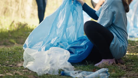 tired little girl collecting trash and plastic bottles from the forest