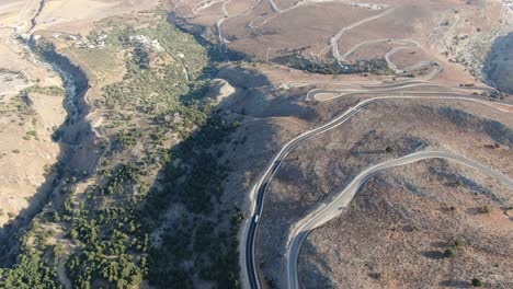 vista de avión no tripulado en grecia volando sobre una montaña marrón y verde con carretera de serpiente y mar en el horizonte en un día soleado