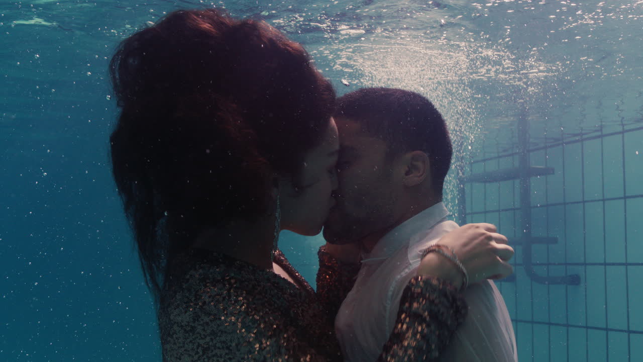 coppia romantica che si bacia sott'acqua in piscina con i vestiti giovani innamorati che si godono un bacio intimo amanti sommersi nell'acqua che galleggiano con bolle in un'intimità passionale