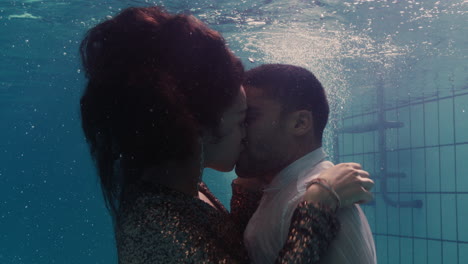 romantic couple kissing underwater in swimming pool wearing clothes young people in love enjoying intimate kiss lovers submerged in water floating with bubbles in passionate intimacy