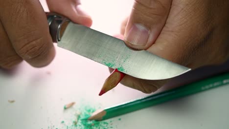 Footage-of-hands-slowly-sharpening-a-pencil-and-some-coloured-pencils-with-a-sharp-knife