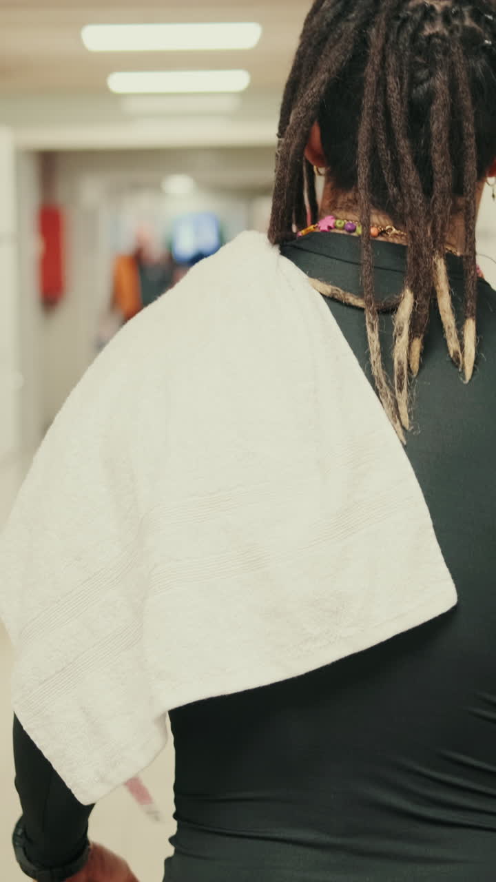 Personne avec des dreadlocks et une serviette marchant dans un couloir