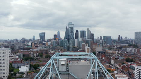 Fly-over-tower-apartment-building,-revealing-downtown-skyline.-Modern-design-futuristic-skyscrapers-in-business-district.-London,-UK