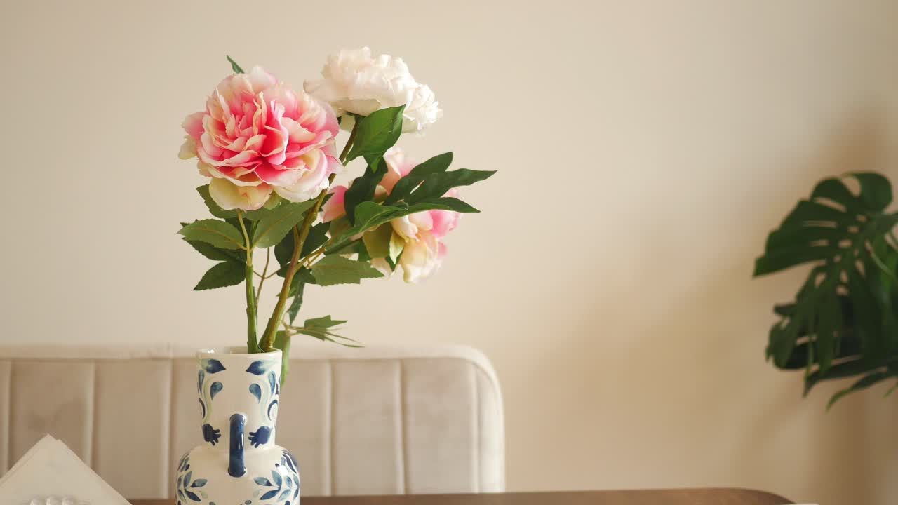 flores rosas y blancas en un jarrón azul y blanco en una mesa