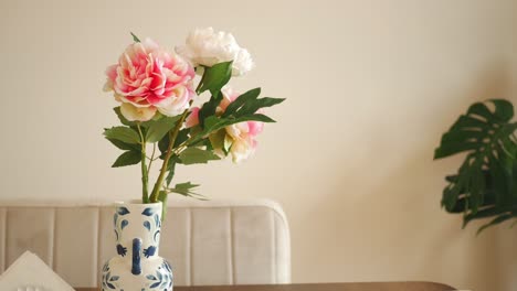 pink and white flowers in a blue and white vase on a table