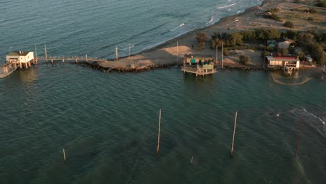 aerial shot of the valleys near ravenna where the river flows into the sea with the typical fishermen's huts at sunset