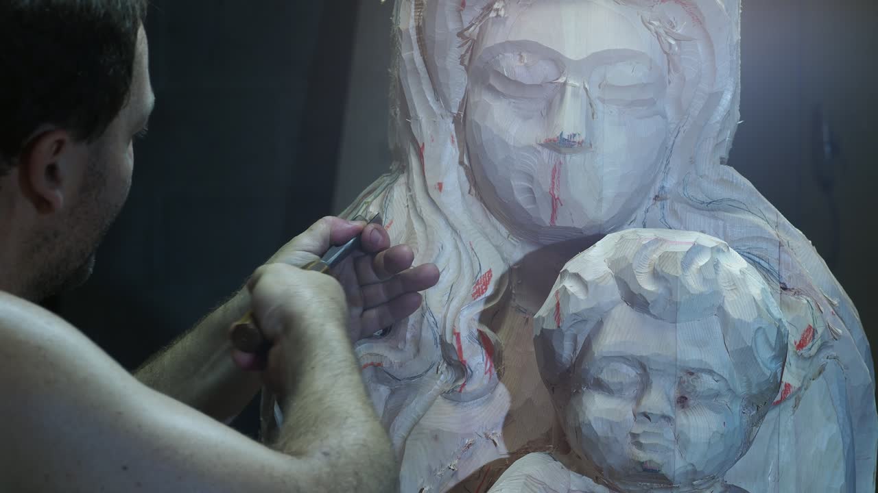 Close-up of a skilled artisan carving a wooden statue of the Madonna and Child with a chisel, showcasing religious art, craftsmanship, and the precision of traditional wood sculpting in progress