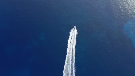 speedboat cuts through deep blue water near italida beach on ano koufonisi in cyclades