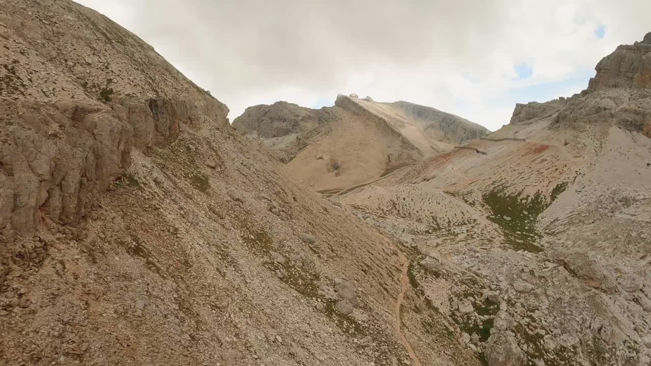 los drones fpv corren hacia el paso de la montaña forcella travenanzes en los dolomitas italianos, recorriendo emocionantemente el suelo en esta persecución aérea de alta velocidad.