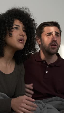 cheerful couple watching sport championship on tv at home