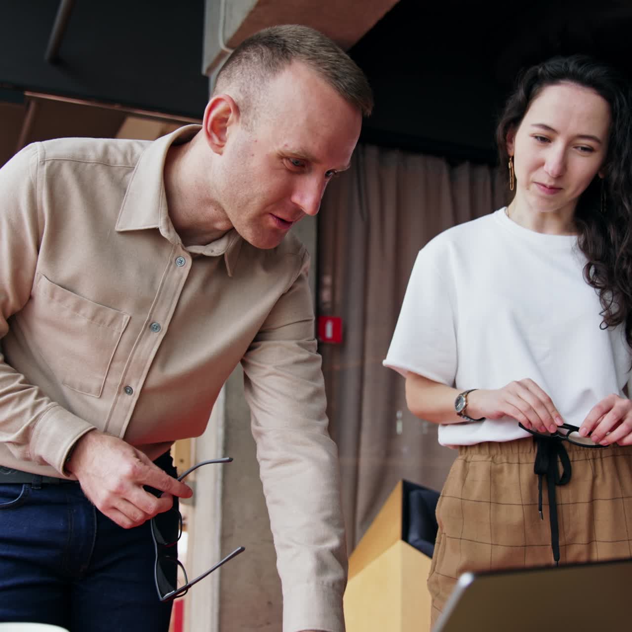 Male and female colleagues collaborating in the office. Workmates look at laptop discussing it. Low angle view