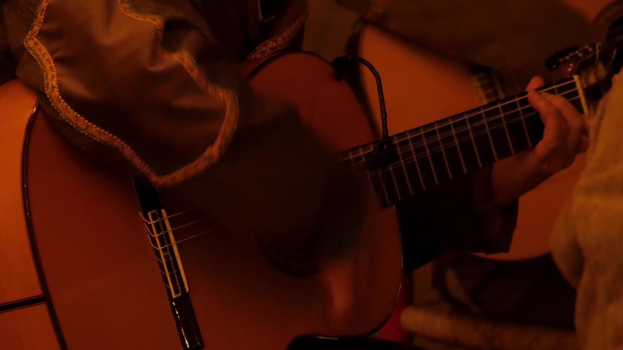Musician strumming acoustic guitar in warm indoor setting, close-up on hands