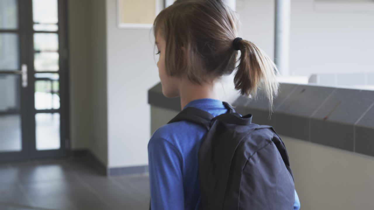 Walking in school hallway, boy with backpack heading to classroom