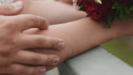 careful guy strokes arm of bride holding bouquet at wedding