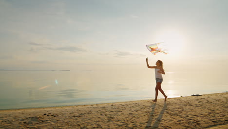 una chica despreocupada corre por la playa jugando con una cometa a cámara lenta