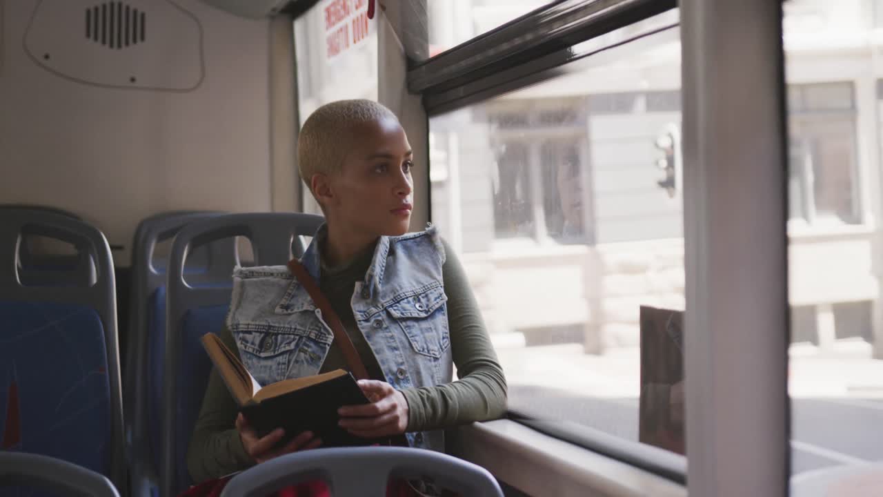 Mixed race woman taking the bus and reading a book