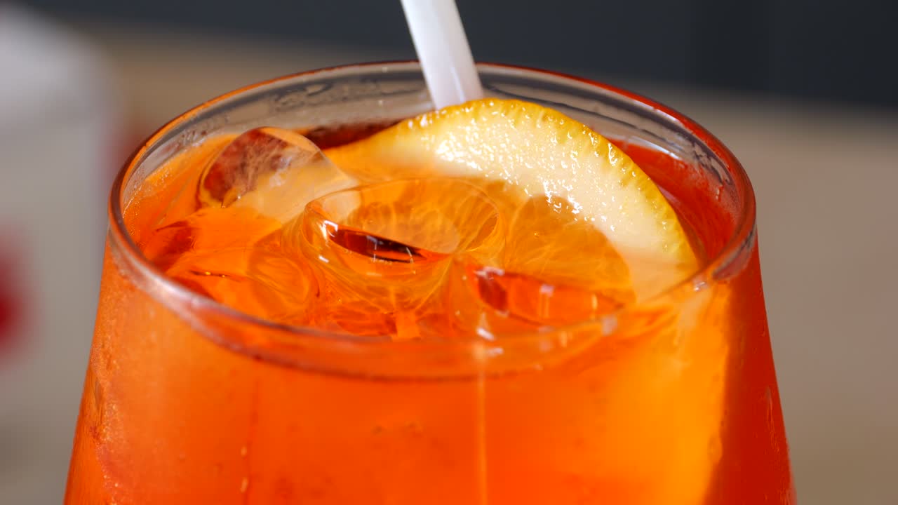 Vista dettagliata di un vivace Aperol Spritz veneziano arancione servito con ghiaccio e guarnito con una fetta d'arancia fresca, ripreso in un primo piano